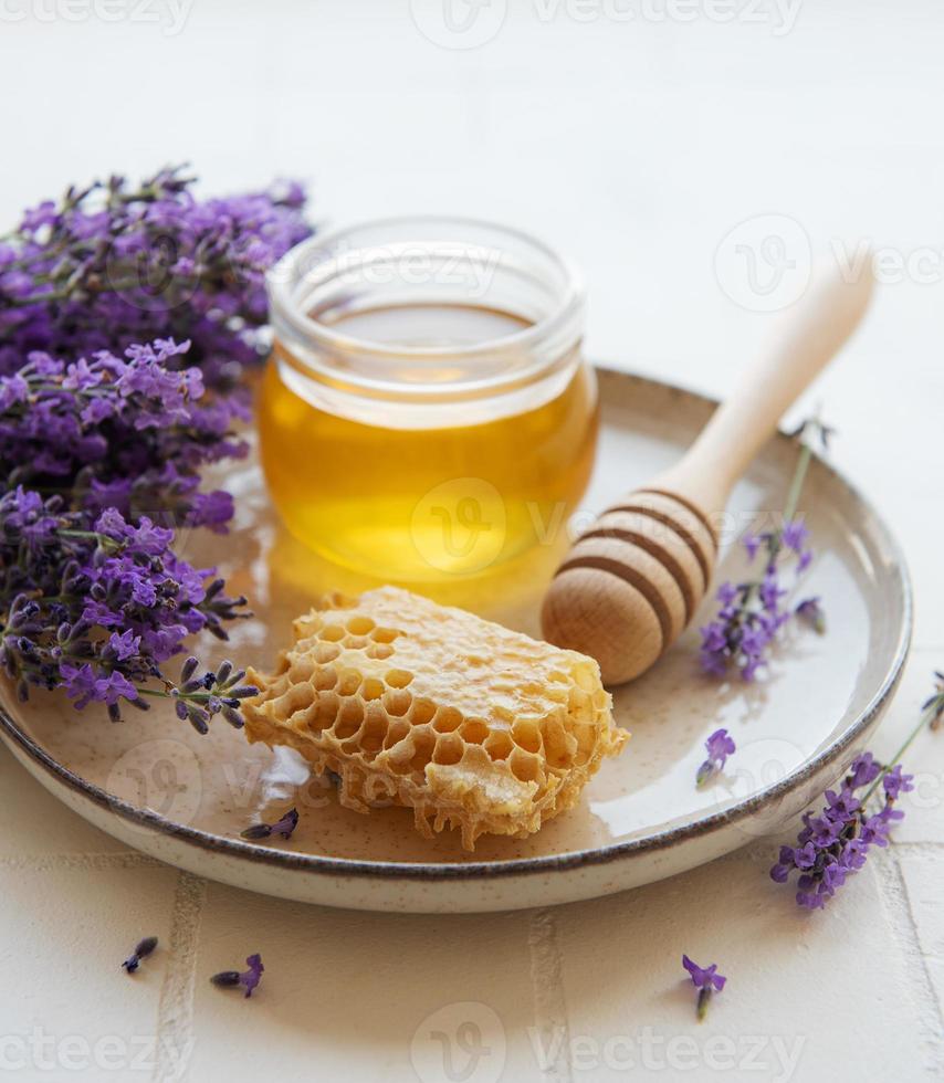 jarra com mel e flores frescas de lavanda foto