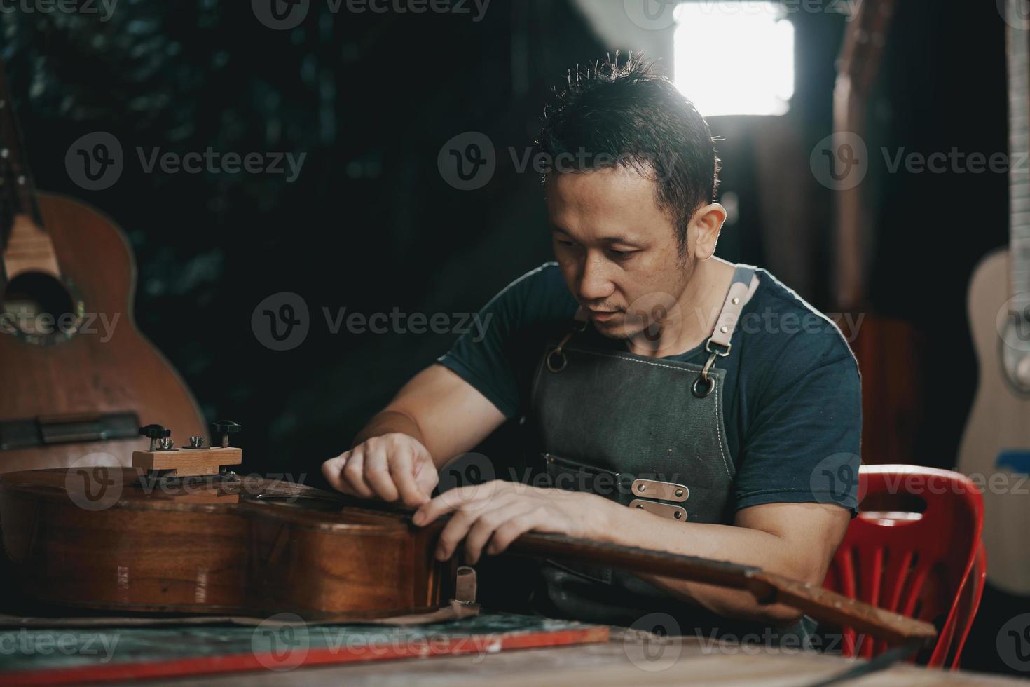 fabricantes de guitarra homem asiático fazendo guitarras acústicas em laboratório. fabricante de guitarra asiático constrói guitarras de alta qualidade para músicos loja de guitarra artesanal. trabalhando bem woodusic, tradição, artesanato antigo. foto