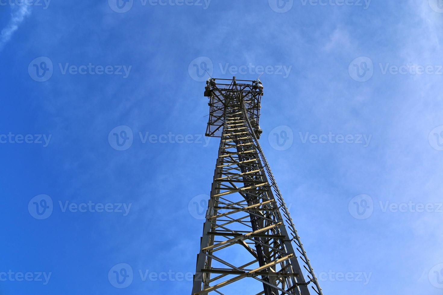 antena elétrica e torre transmissora de comunicação em uma paisagem do norte da Europa contra um céu azul foto