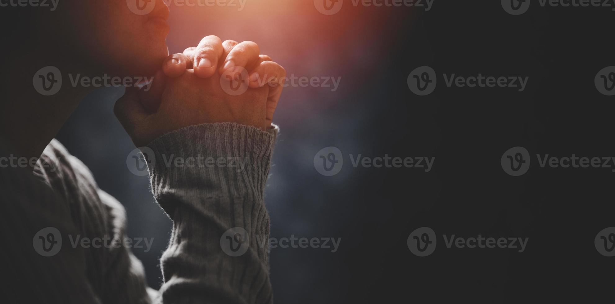 religião de cristo e cristianismo adoram ou rezam o conceito. mulher católica cristã está orando a Deus no escuro na igreja. pessoa de oração mão em fundo preto. menina acreditar e fé em jesus cristo. foto