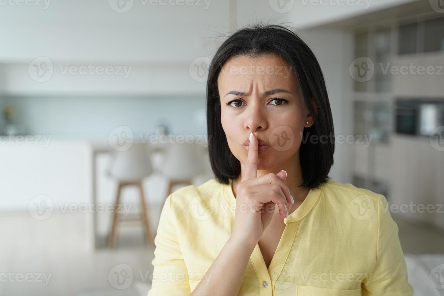 jovem séria carrancuda mostra gesto de silêncio, pedindo para manter a privacidade, segredo e silêncio em casa foto