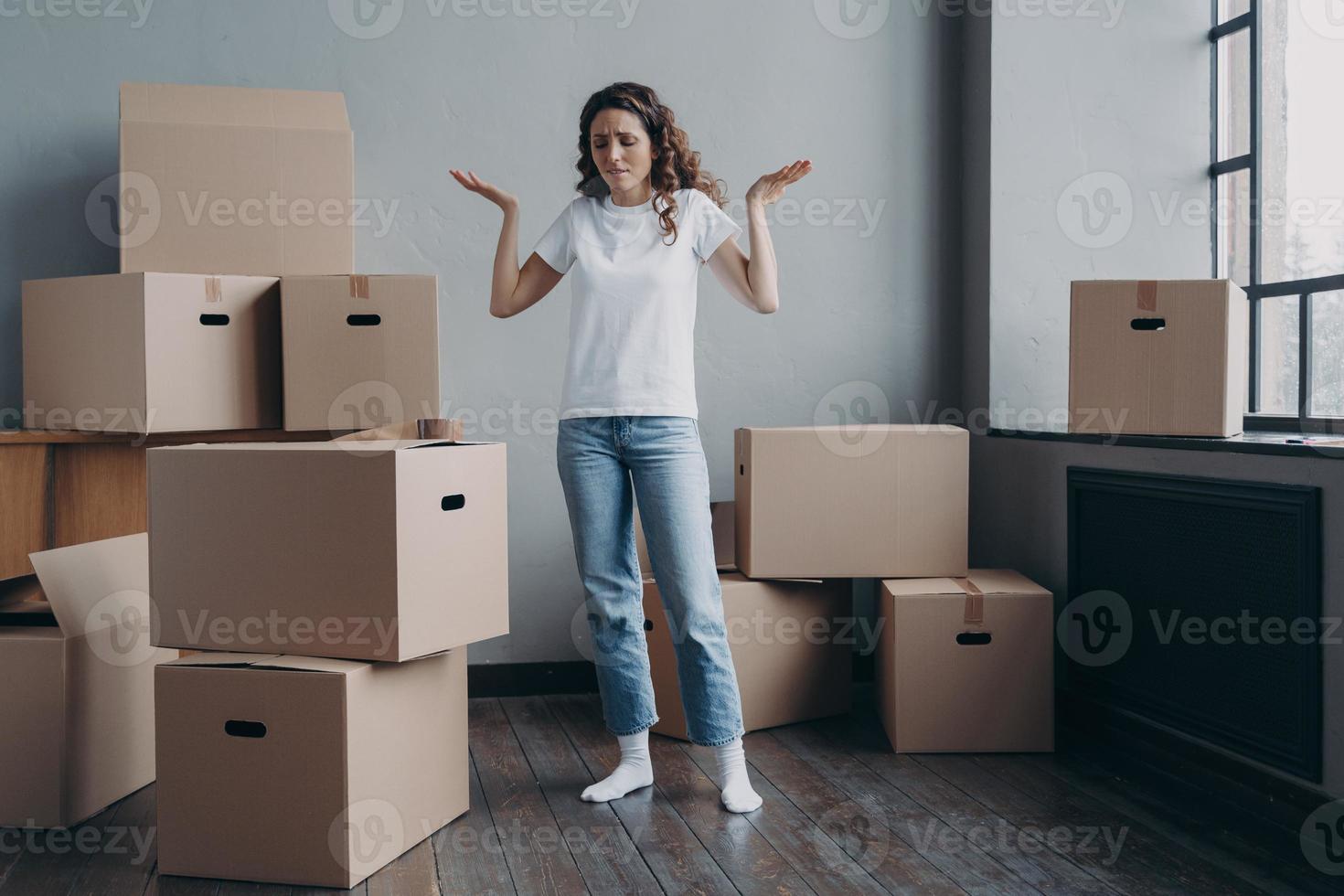 mulher cansada intrigada com caixas de papelão se sente exausta de se mudar para uma nova casa. dia de realocação difícil foto