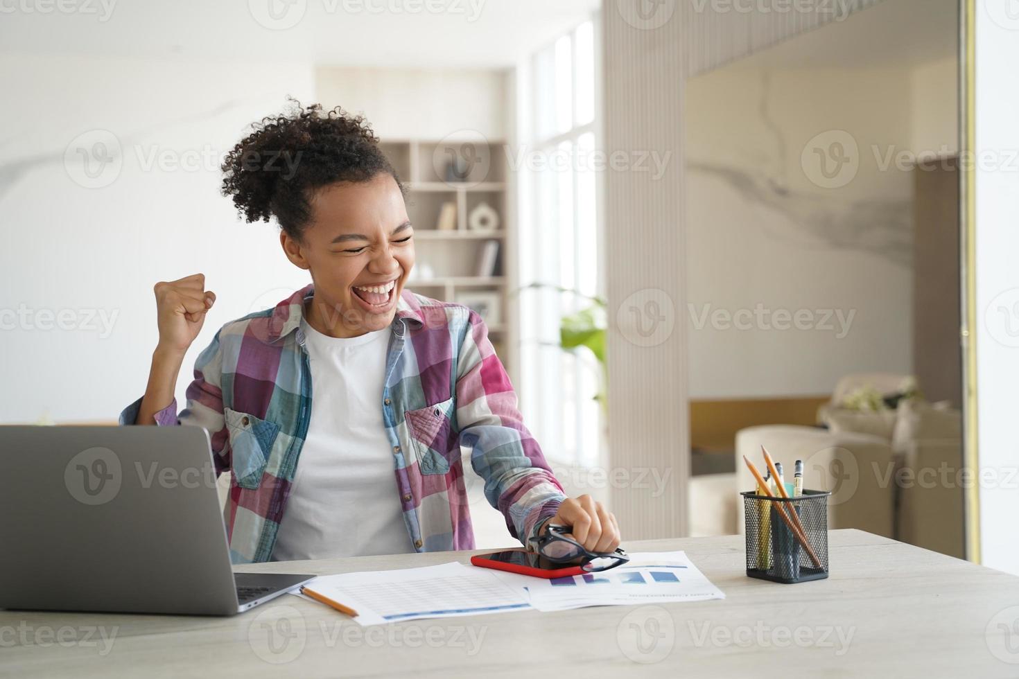 estudante adolescente de raça mista animada recebeu e-mail de boas notícias no laptop comemora conquista pessoal foto