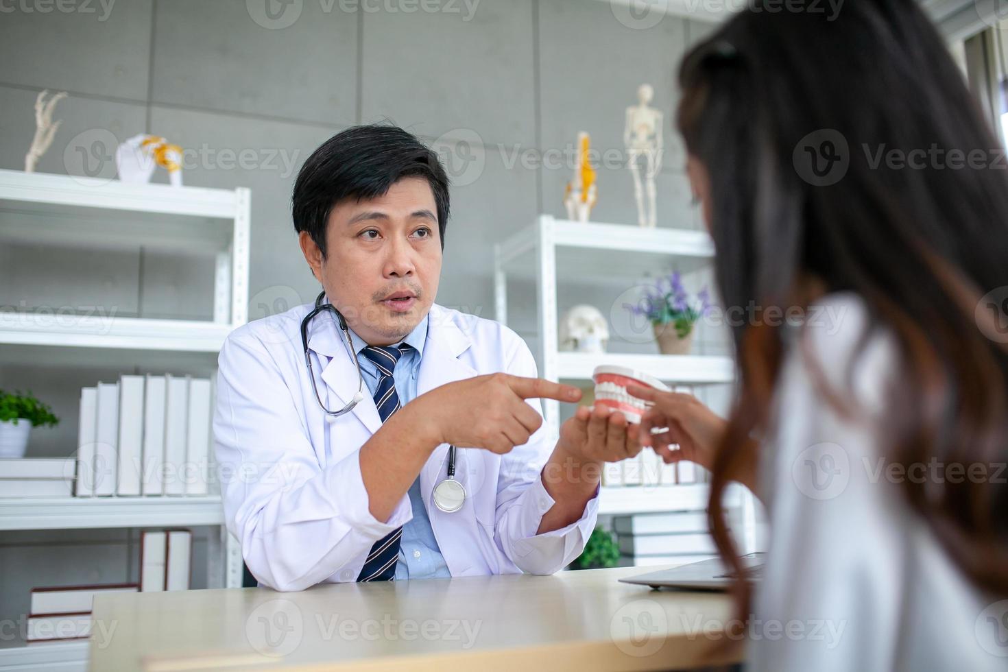 o dentista está explicando sobre a saúde bucal, mostrando os defeitos radiculares dos pacientes antes de corrigir com o modelo. foto