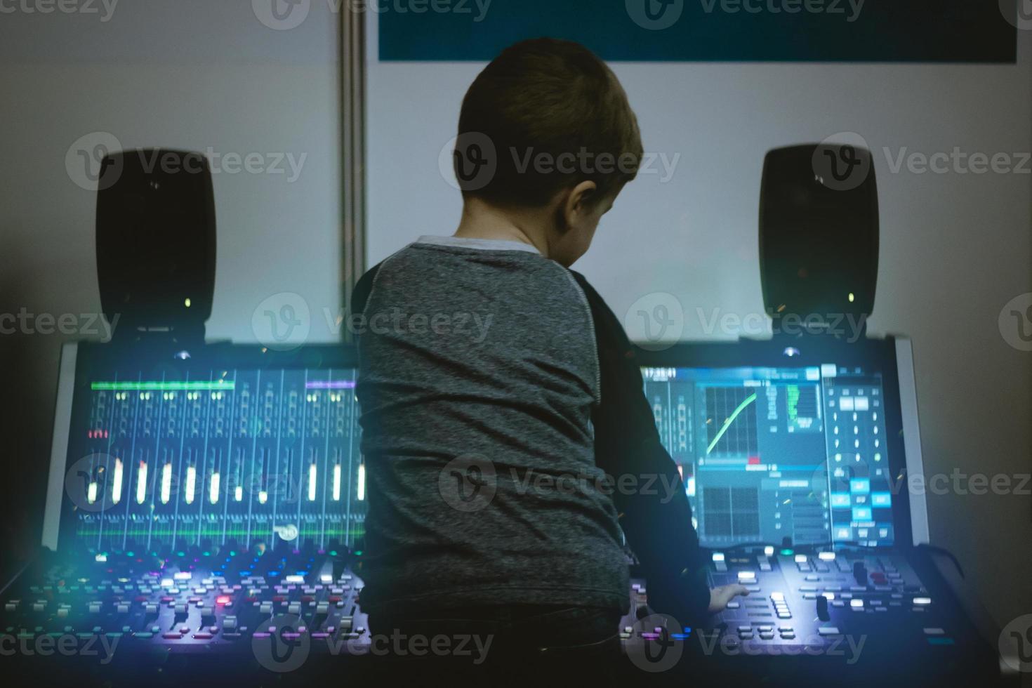 vista traseira do menino no mixer de áudio no estúdio de gravação. foto