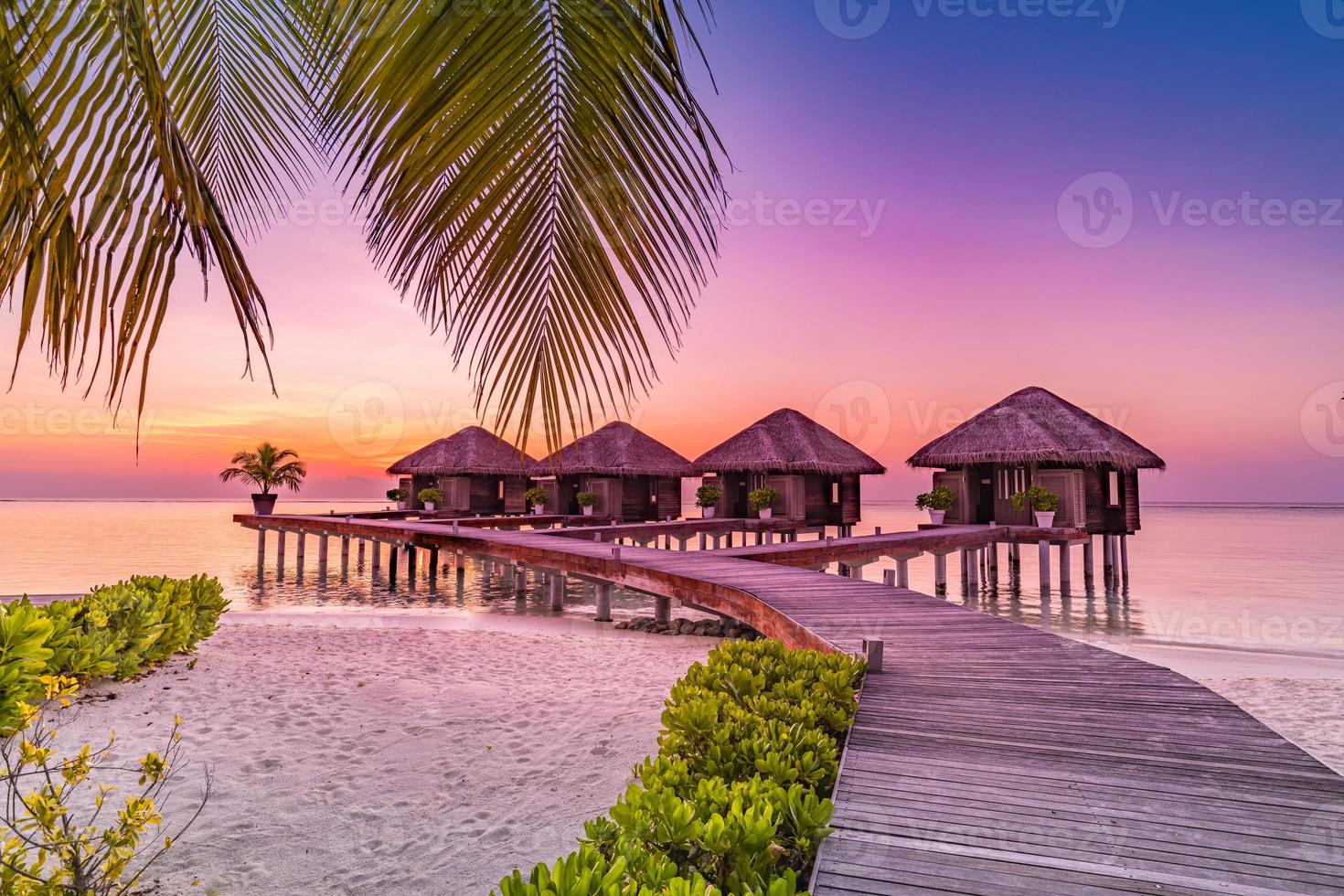 pôr do sol da ilha maldivas. resort de bangalôs de água na praia das ilhas. oceano índico, maldivas. bela paisagem por do sol, villas de resort de luxo e céu colorido. férias de férias de verão e conceito de viagens foto