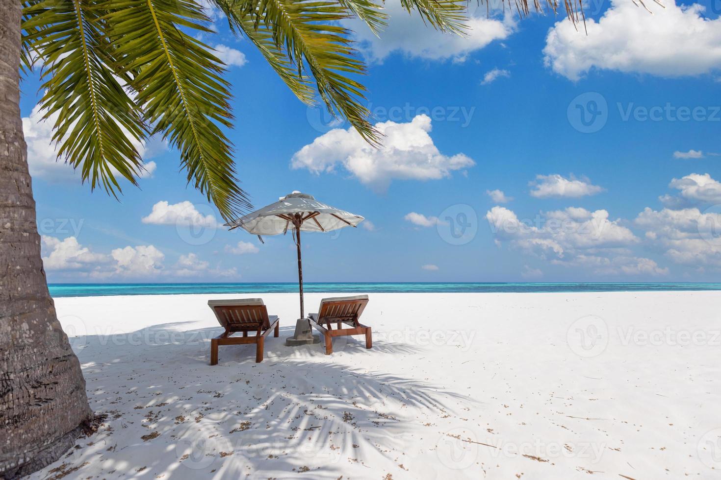 praia de férias incrível. cadeiras na praia de areia perto do mar. conceito de férias românticas de verão para turismo. paisagem de ilha tropical. cenário tranquilo da costa, relaxe o horizonte à beira-mar de areia, folhas de palmeira foto