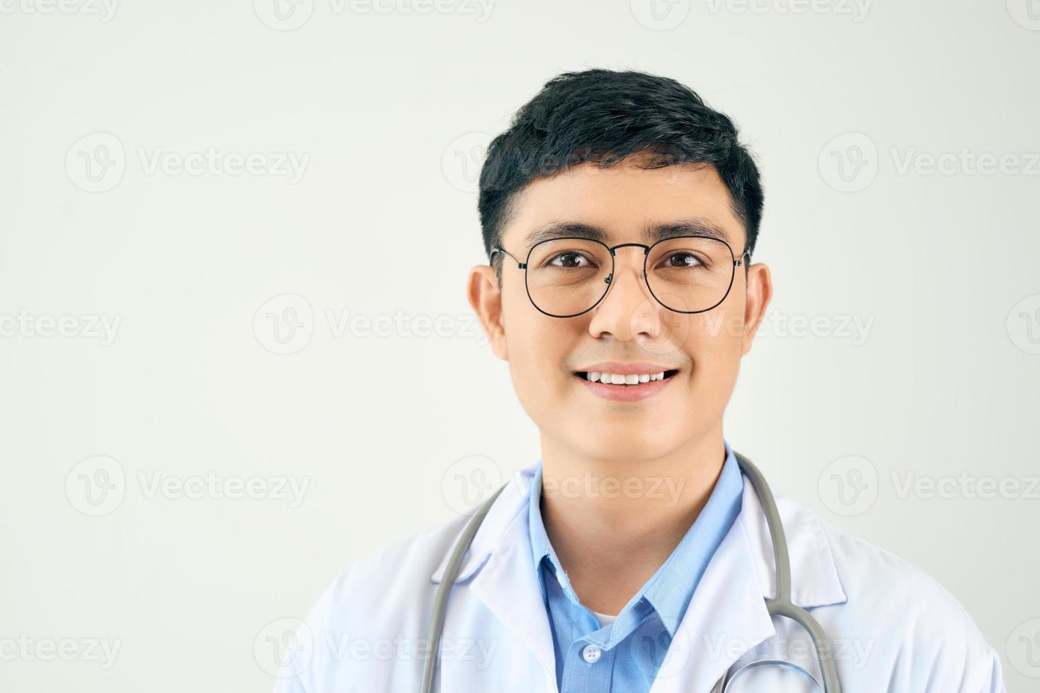 um médico bonito com estetoscópio em pé com confiança no fundo branco foto