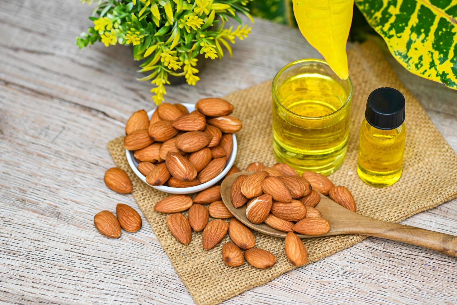 óleo de amêndoa e amêndoas na mesa, delicioso óleo de amêndoas doces em garrafa de vidro, amêndoa torrada para alimentos saudáveis e lanches óleos vegetais orgânicos para cozinhar ou spa foto