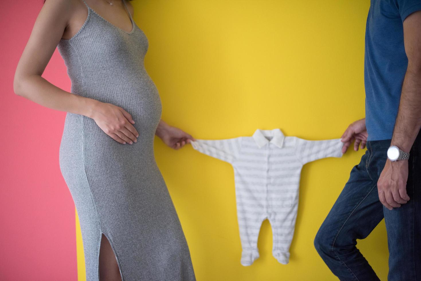 jovem casal segurando roupas de bebê foto