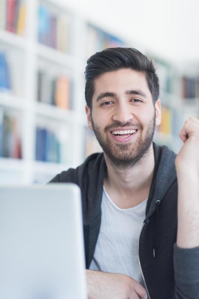 estudante na biblioteca da escola usando laptop para pesquisa foto