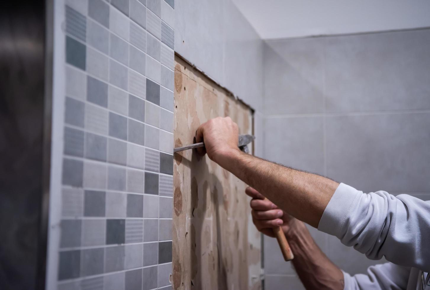 trabalhador remover demolir azulejos antigos em um banheiro foto