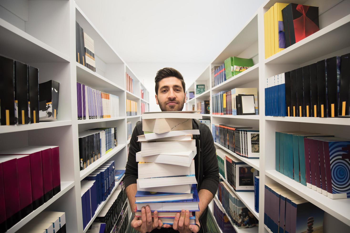 estudante segurando muitos livros na biblioteca da escola foto