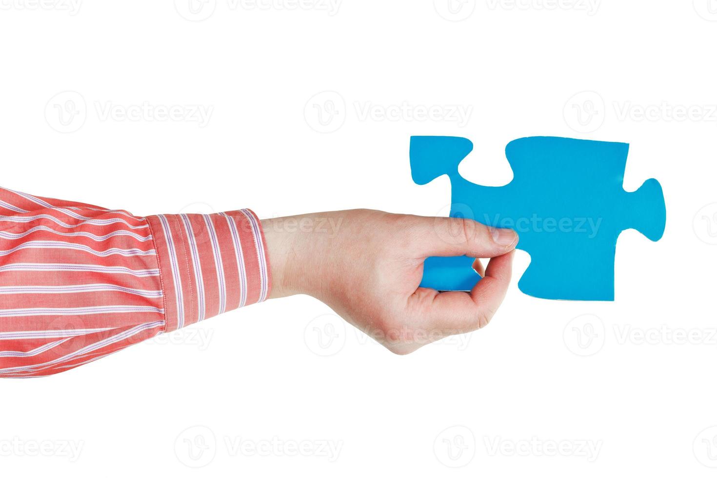 mão masculina segurando grande peça de quebra-cabeça de papel azul foto