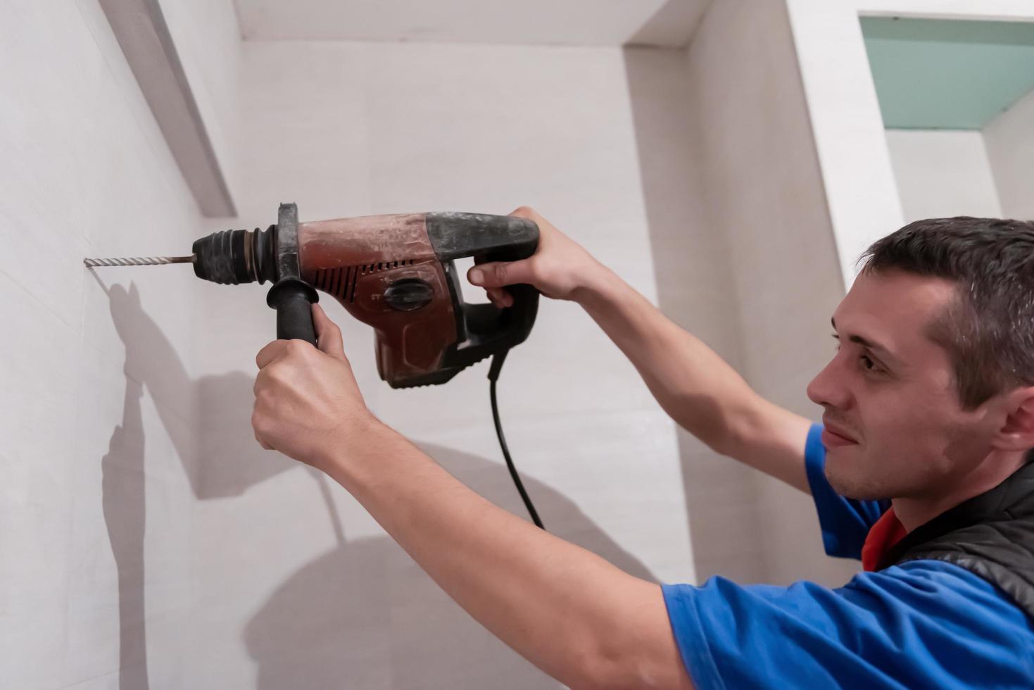 trabalhador da construção civil fazendo furos no banheiro foto