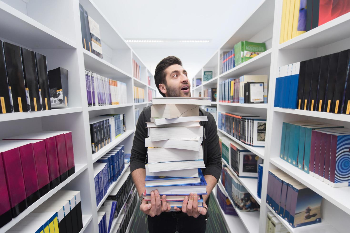 estudante segurando muitos livros na biblioteca da escola foto