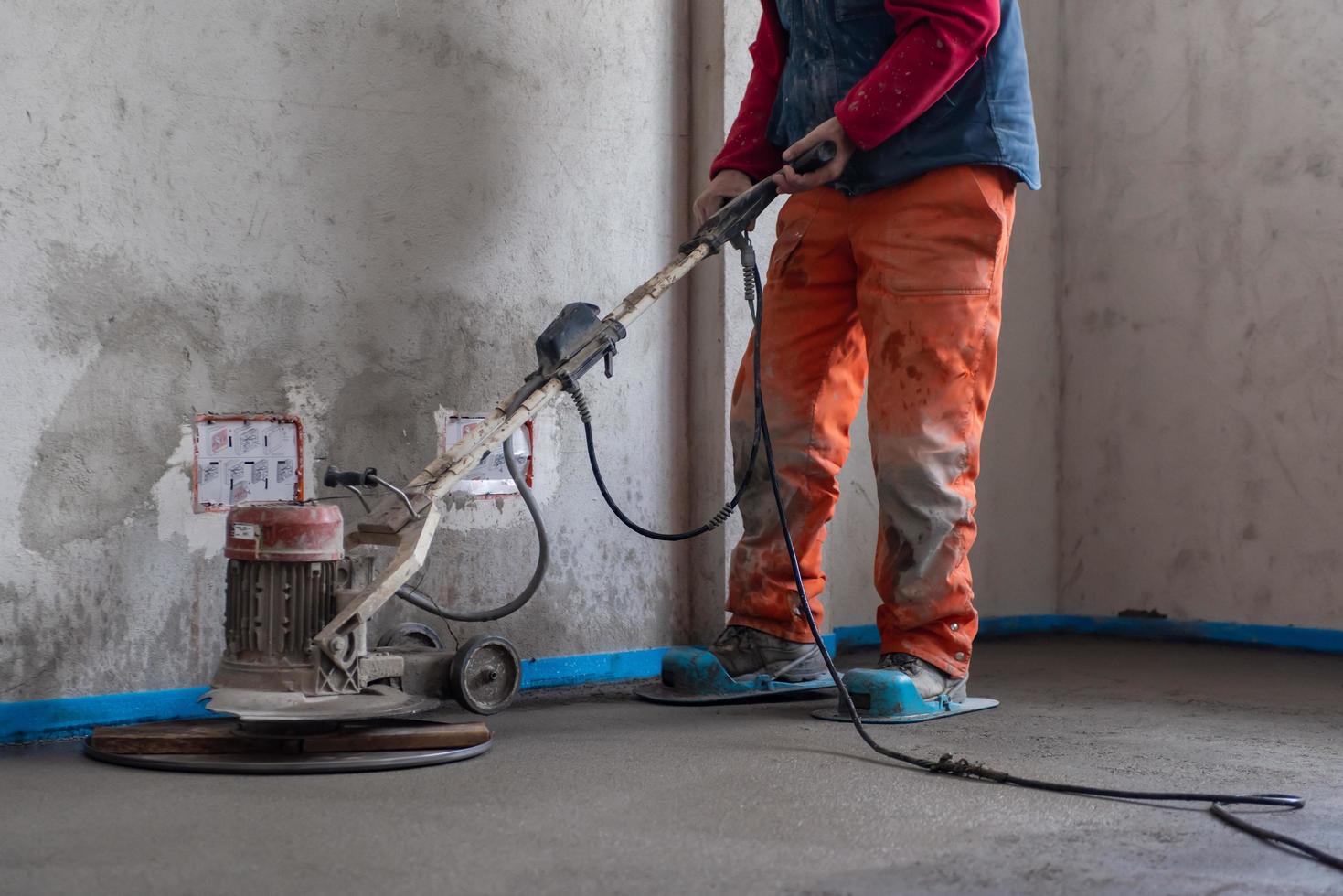 trabalhador realizando e polindo piso de betonilha de areia e cimento foto