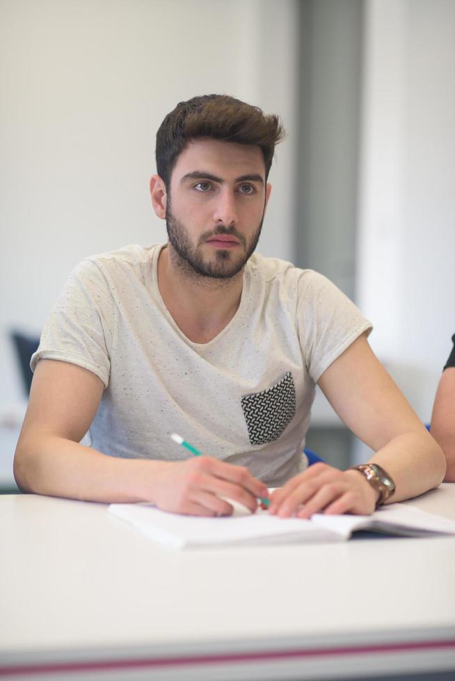 estudante do sexo masculino tomando notas em sala de aula foto