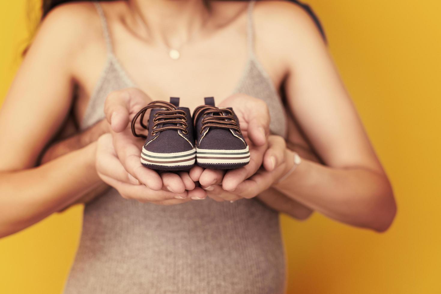 casal segurando sapatos de bebê recém-nascido foto