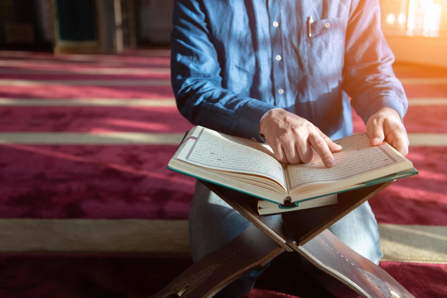 homem muçulmano rezando sozinho a Deus dentro da mesquita e lendo o livro islâmico de azevinho foto