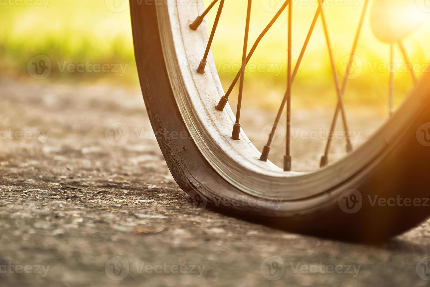 close-up vista da bicicleta que tem pneu furado e estacionado na calçada, fundo desfocado. foco suave e seletivo no pneu. foto