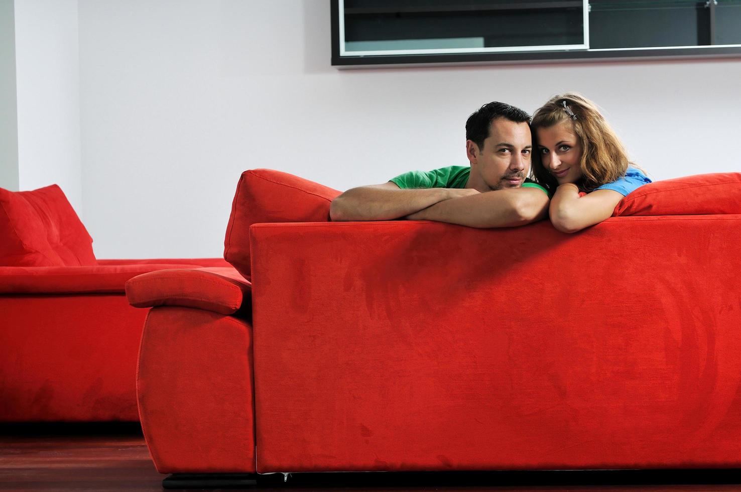 casal feliz relaxa no sofá vermelho foto