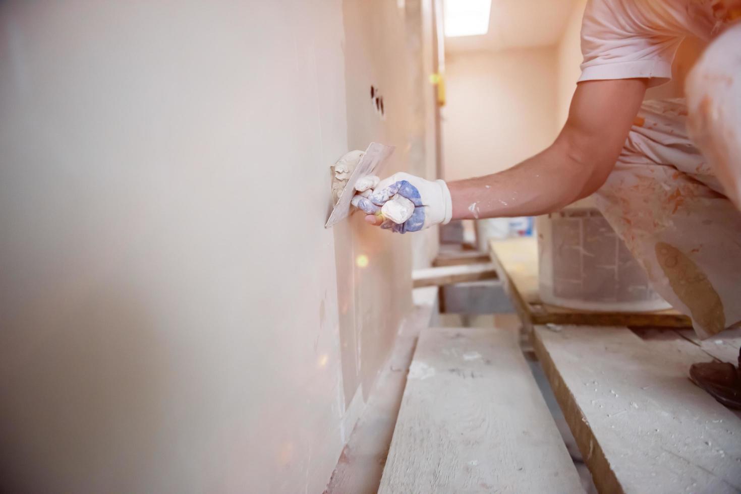 trabalhador da construção civil reboco em paredes de gesso foto