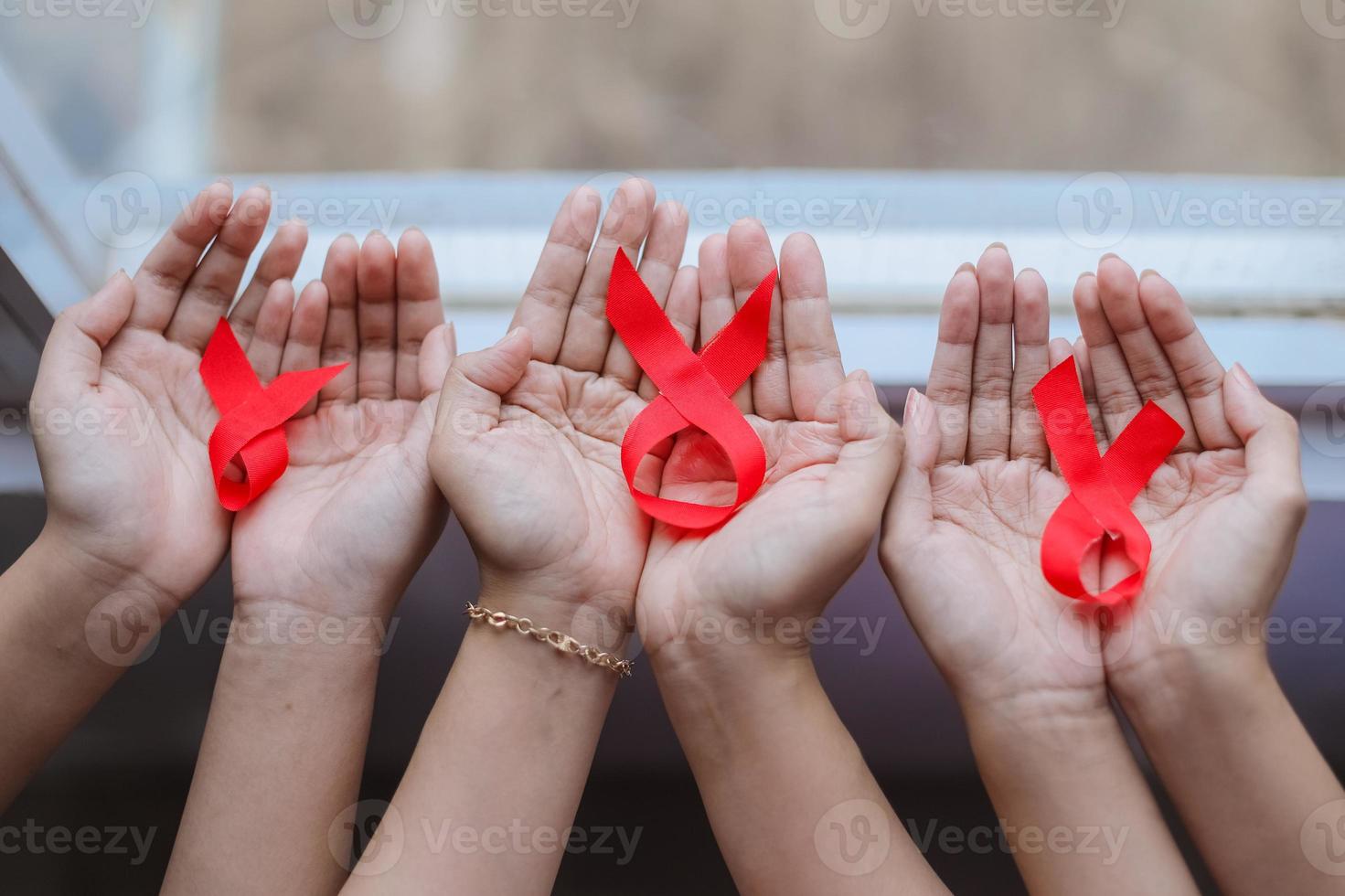 muitas mãos segurando fitas vermelhas para aids ou fundo de campanha de câncer foto