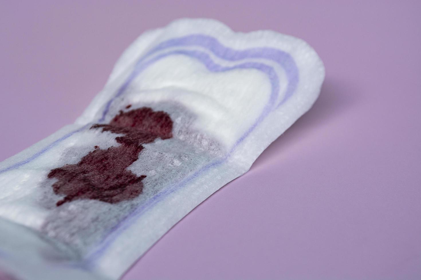 sangue menstrual em um absorvente em fundo rosa. postura plana foto