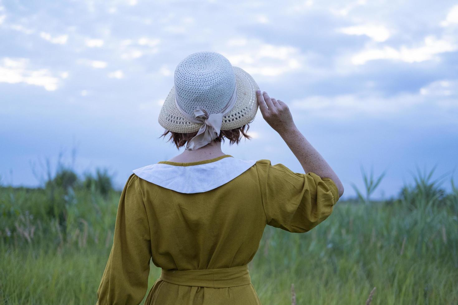 Mulher jovem ruiva com sardas em vestido vintage feito à mão anda em campos com flores foto