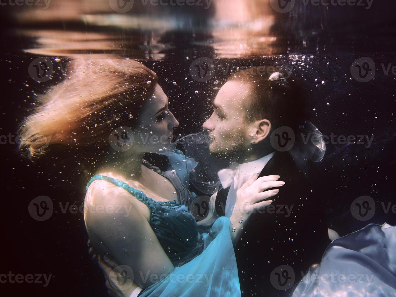 lindo casal dançando debaixo d'água na piscina foto