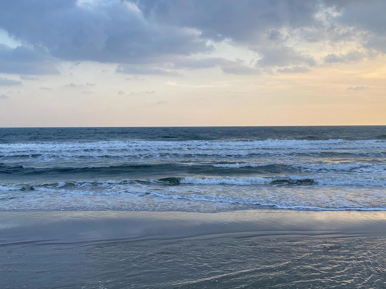 belo pôr do sol sobre a onda da praia foto