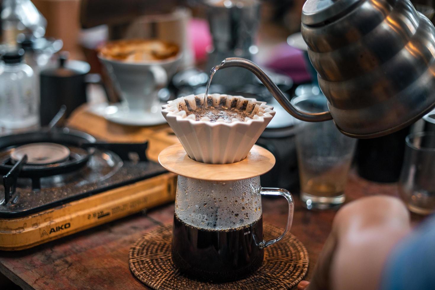 café por gotejamento, barista derramando água no café moído com filtro foto