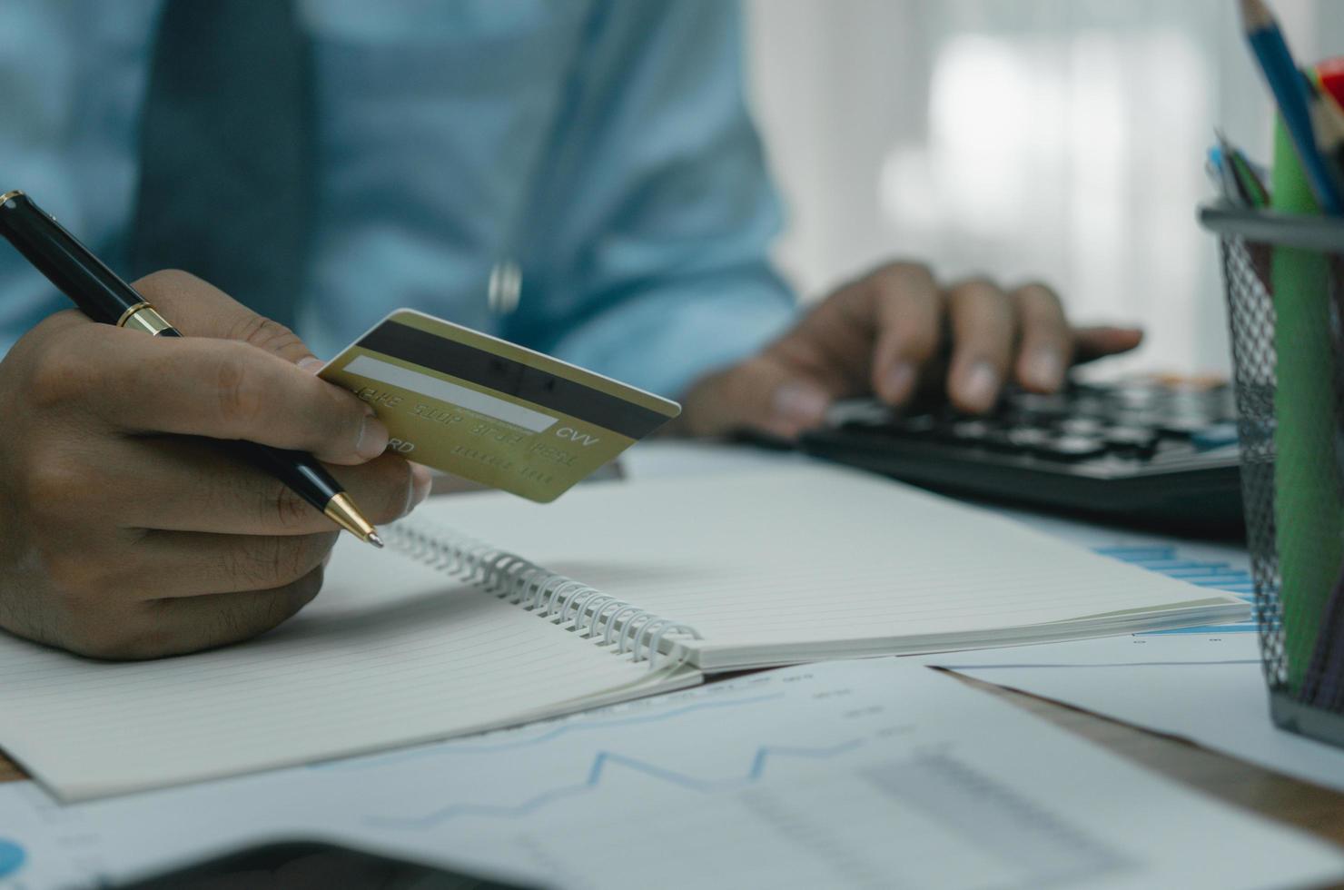 homem segurando o cartão de crédito com o conceito de negócio de comércio on-line de finanças de pagamento de calculadora. foto