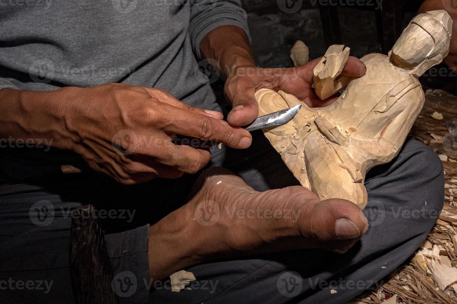mãos trabalhando e esculpindo buda de madeira close-up foto