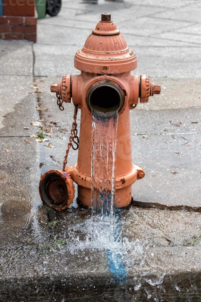 hidrante de rua laranja espalhando água na rua foto