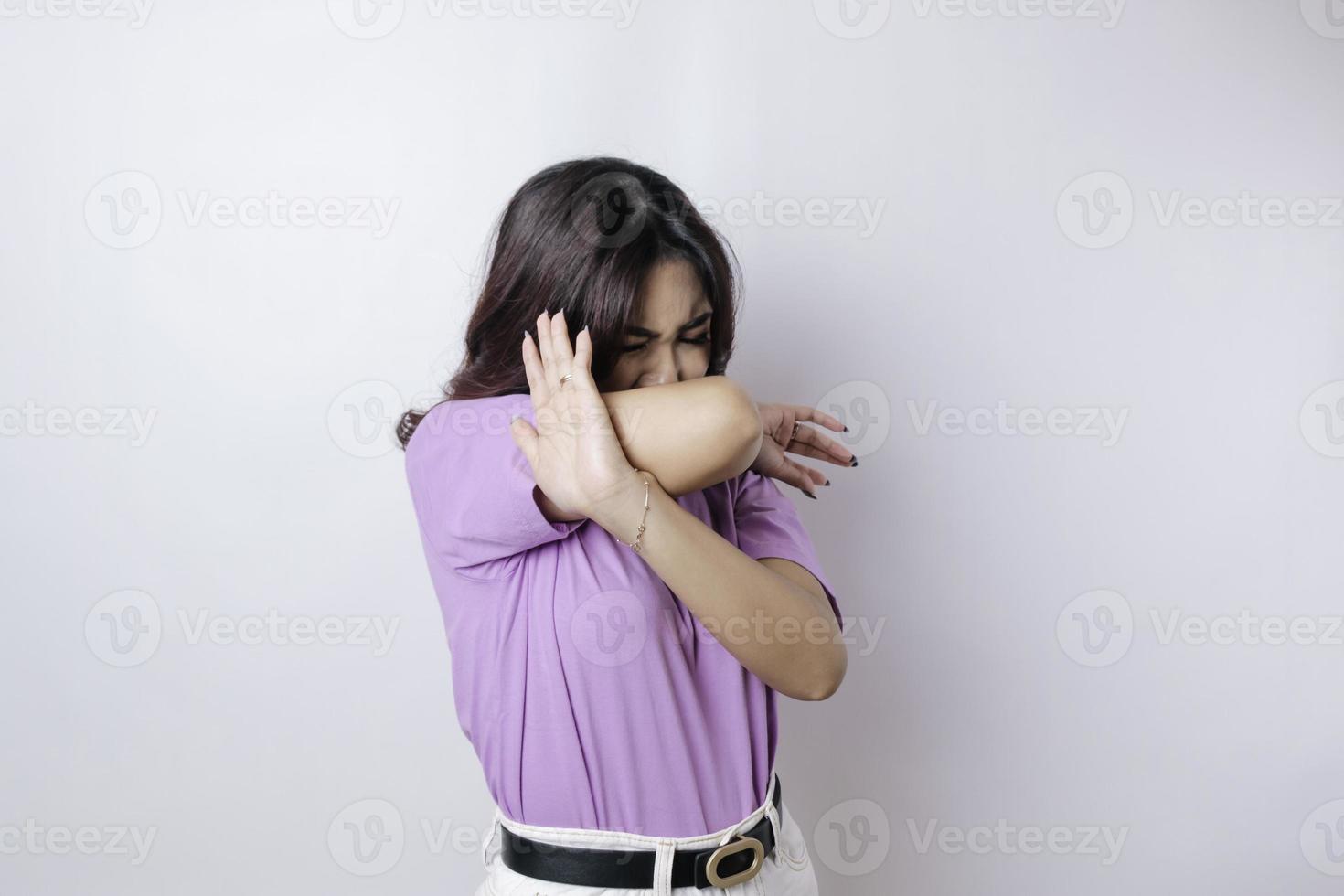 jovem mulher asiática isolada no fundo branco, parece deprimida, rosto coberto por dedos assustados e nervosos. foto