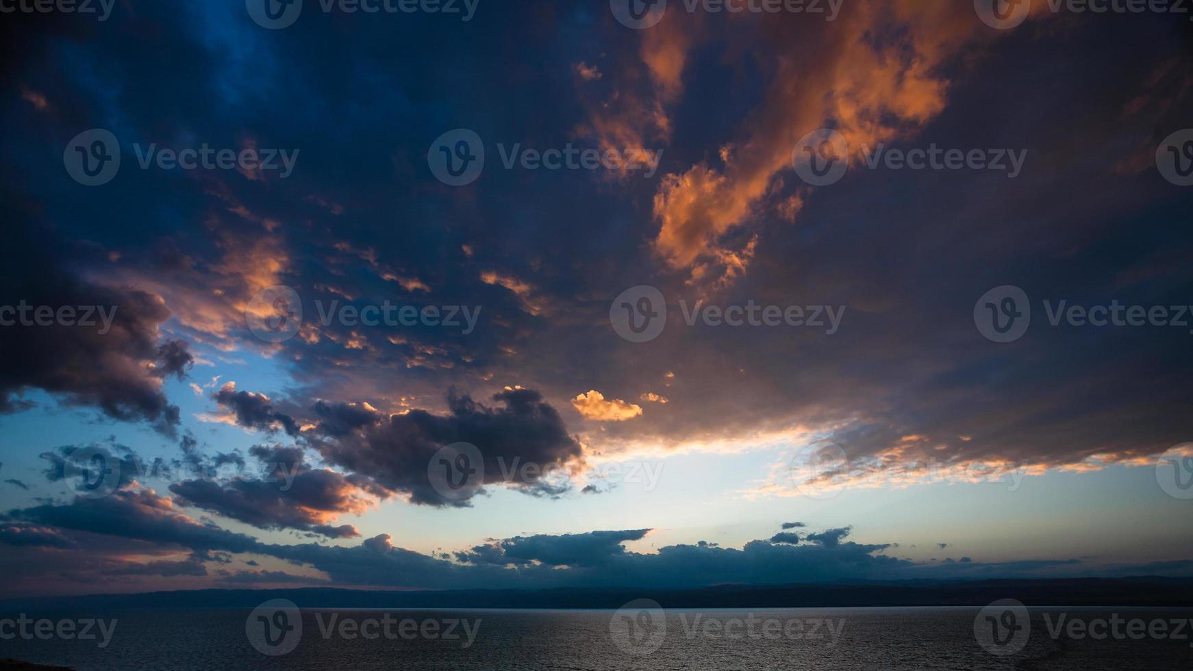 pôr do sol em nuvens escuras sobre o mar morto no inverno foto