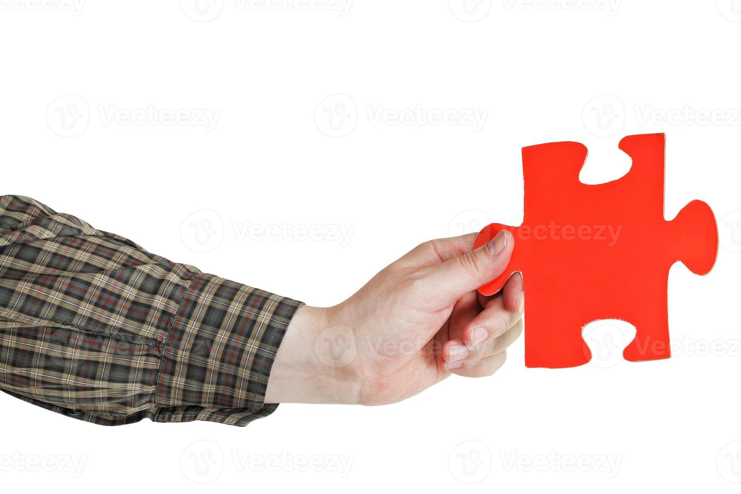 mão masculina segurando grande peça de quebra-cabeça de papel vermelho foto