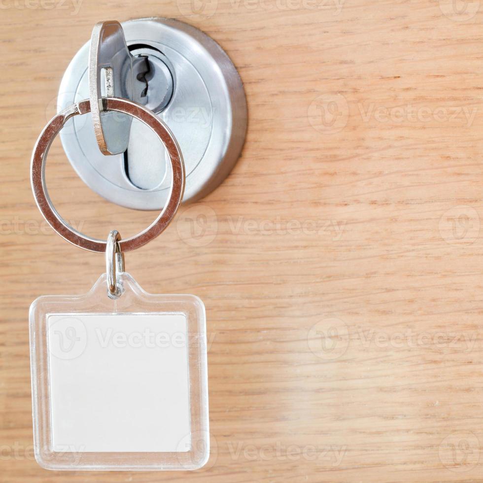 chave de casa com chaveiro quadrado em branco na fechadura foto