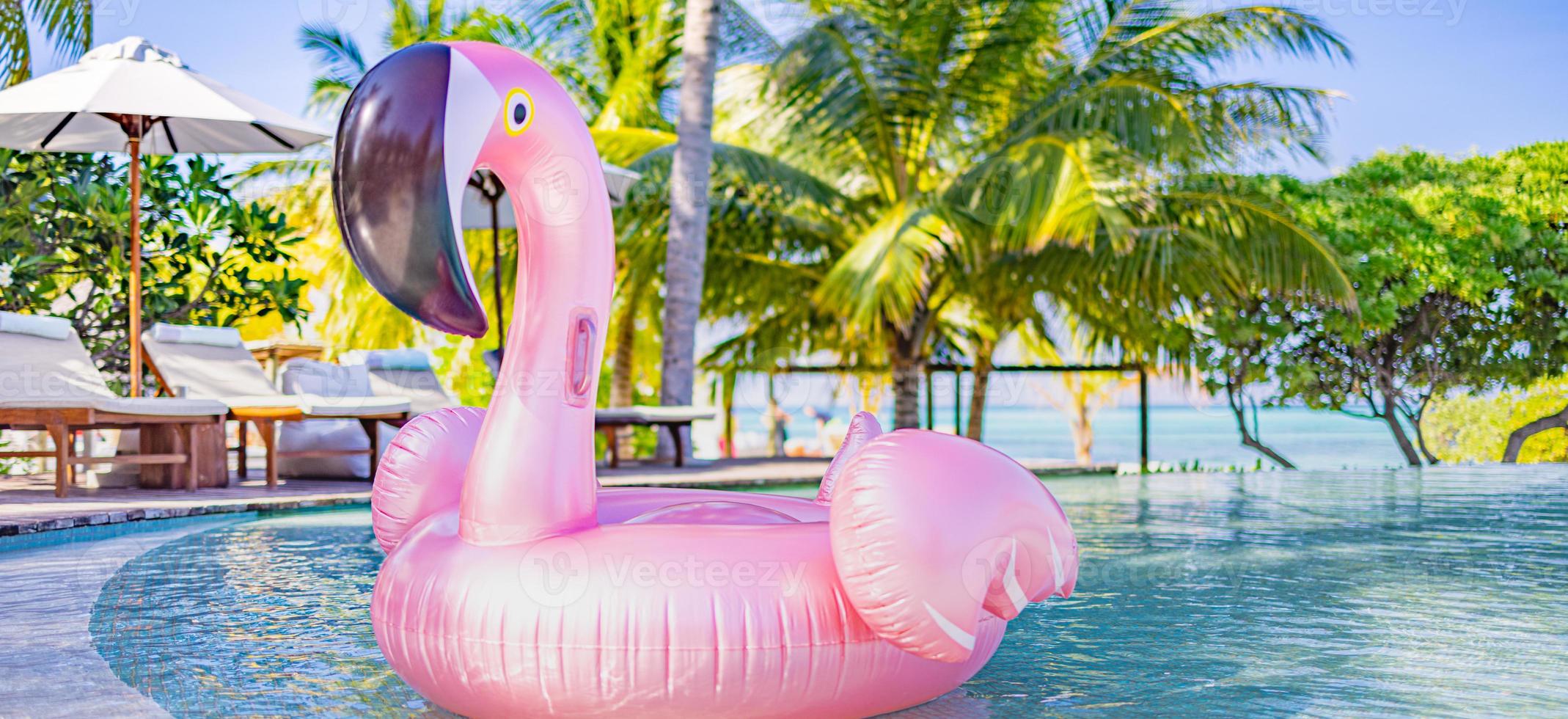 diversão de verão no resort tropical, cadeiras, espreguiçadeiras com guarda-chuva sob palmeiras. água de piscina de flamingo inflável rosa, panorama de praia de verão. viagens de estilo de vida de luxo, banner de férias de verão foto