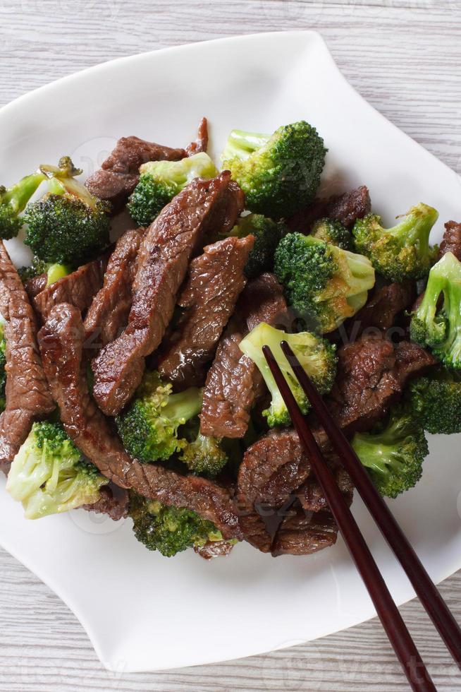 carne asiática com brócolis e pauzinhos. vista superior vertical foto
