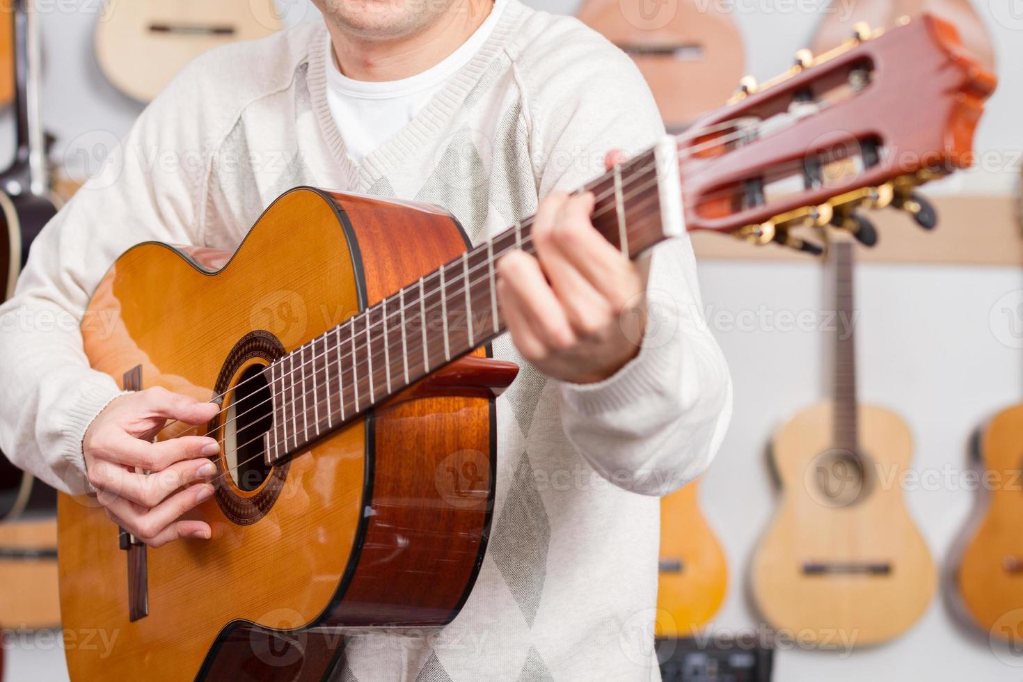 homem tocando violão na loja de música foto