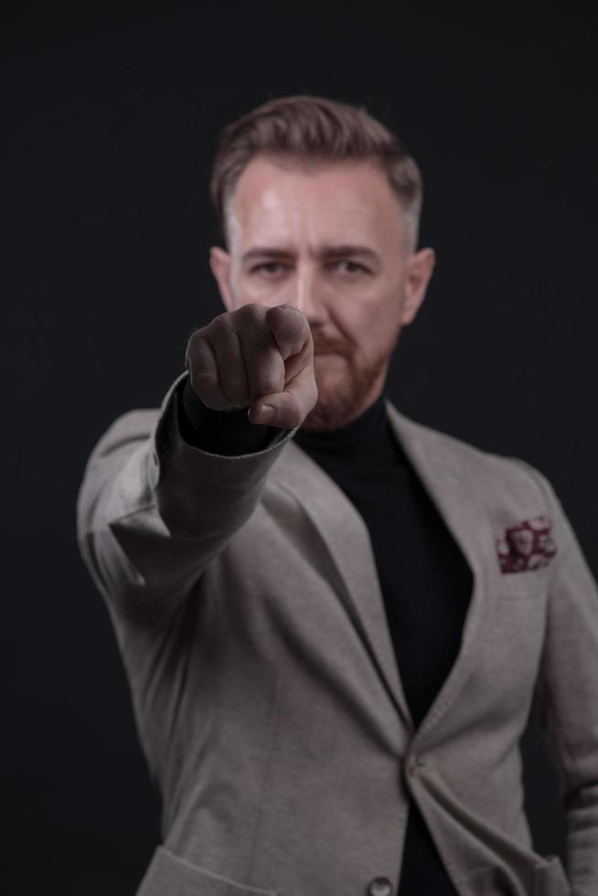 retrato de um elegante elegante empresário sênior com barba e roupas de negócios casuais em estúdio fotográfico isolado em fundo escuro, gesticulando com as mãos foto