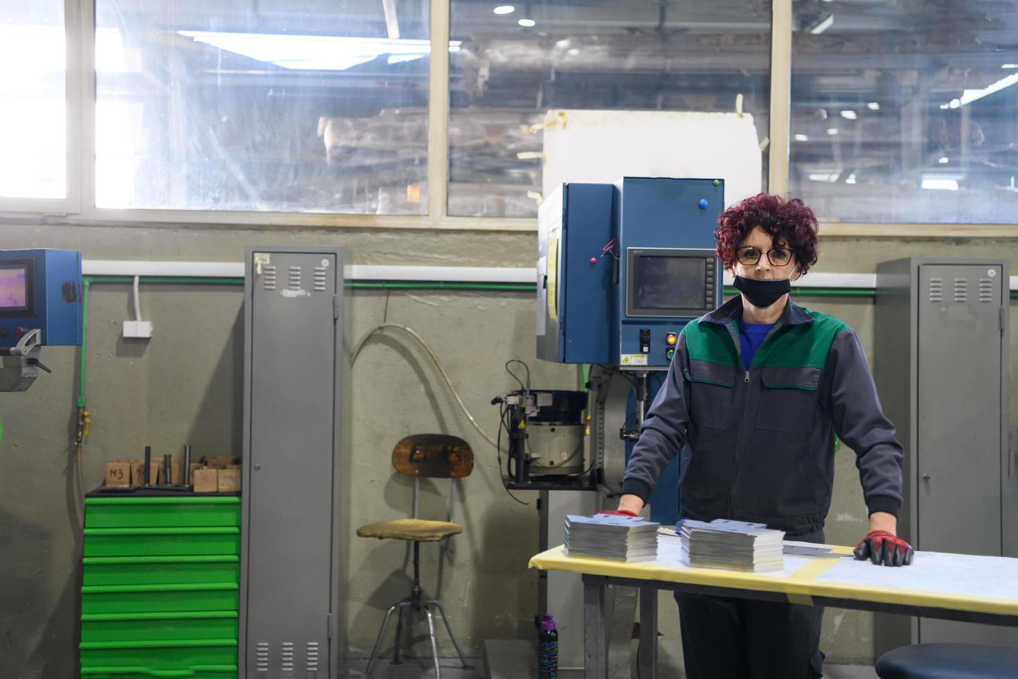 mulher trabalhando em uma fábrica moderna e preparando material para uma máquina cnc. foto