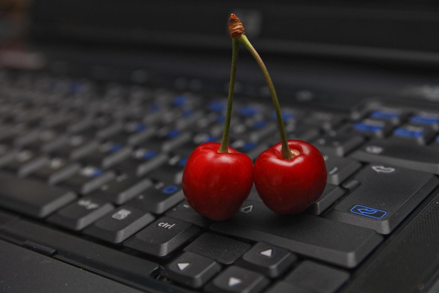 cereja fresca no teclado do laptop foto