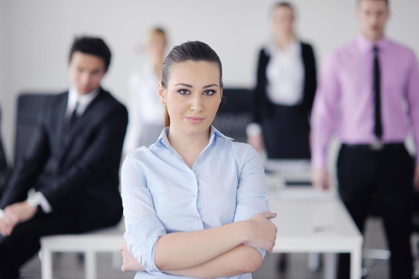 mulher de negócios em pé com sua equipe em segundo plano foto