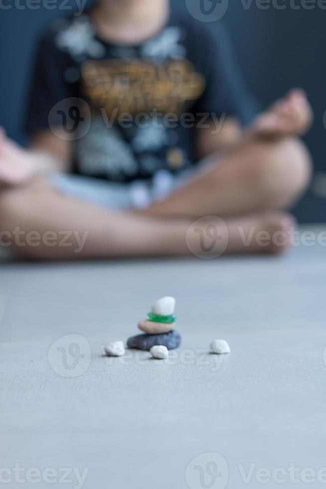 pilha de pedras de seixo tipo zen com criança meditando em segundo plano. foto