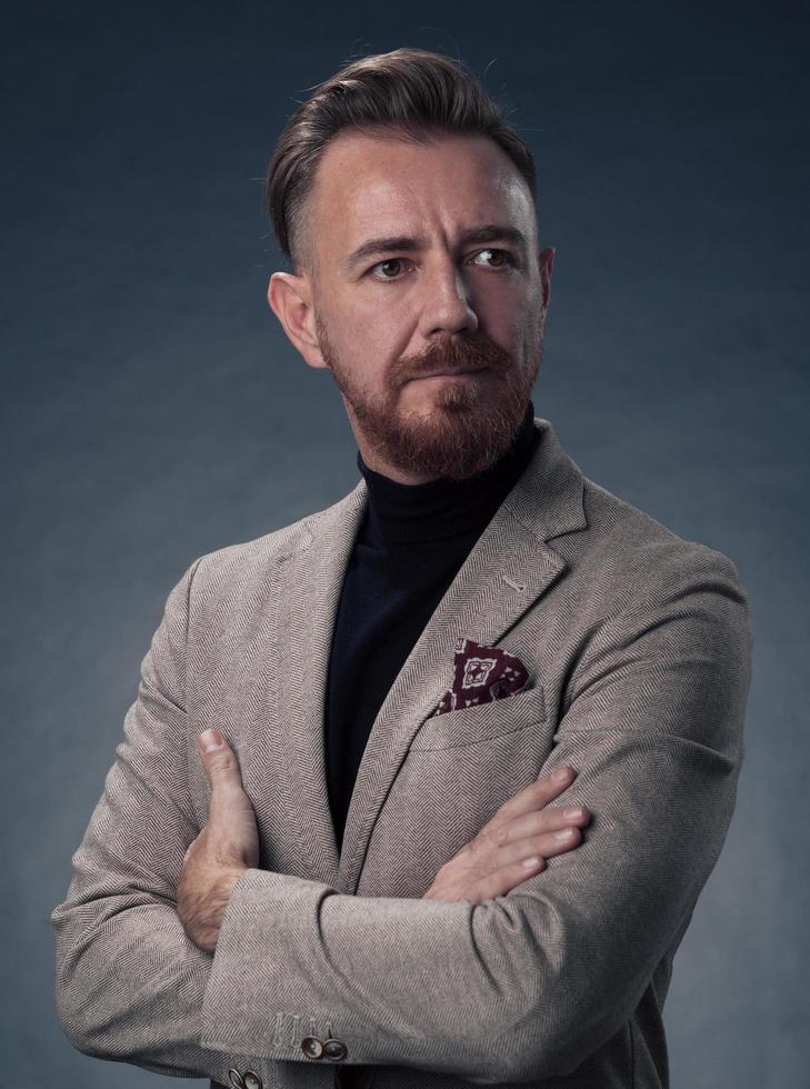 retrato de um elegante elegante empresário sênior com barba e roupas de negócios casuais em estúdio fotográfico isolado em fundo escuro, gesticulando com as mãos foto