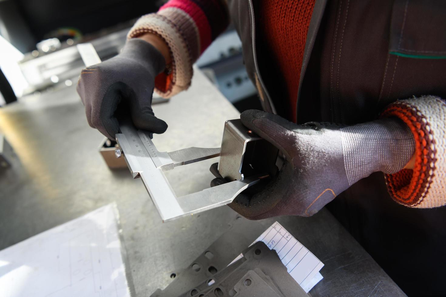 uma mulher que trabalha em uma moderna fábrica de produção e processamento de metais, preparando e medindo materiais que vão para o processamento de máquinas cnc foto